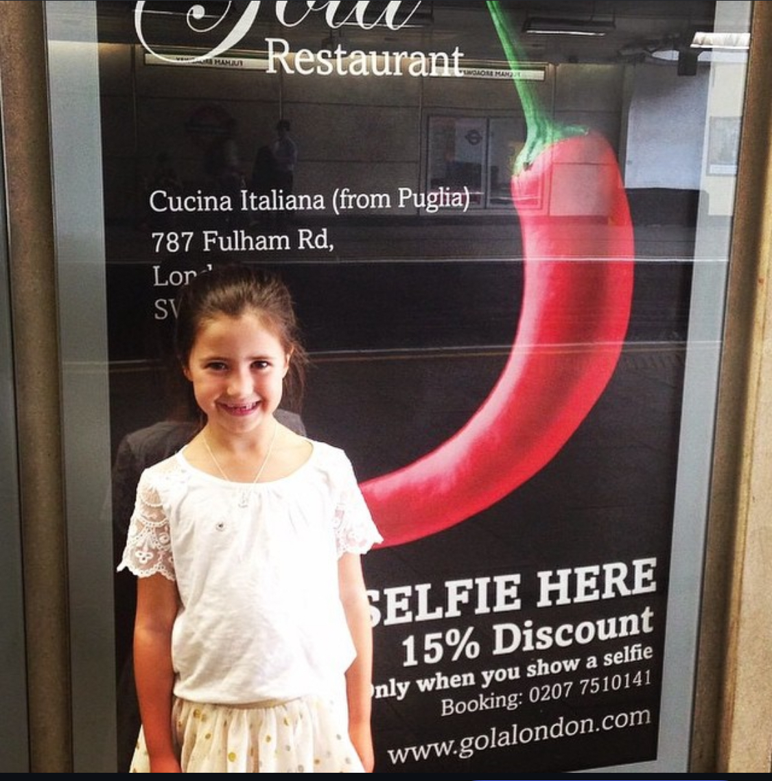 A young guest beside the Gola restaurant sign advertising a 15% selfie discount