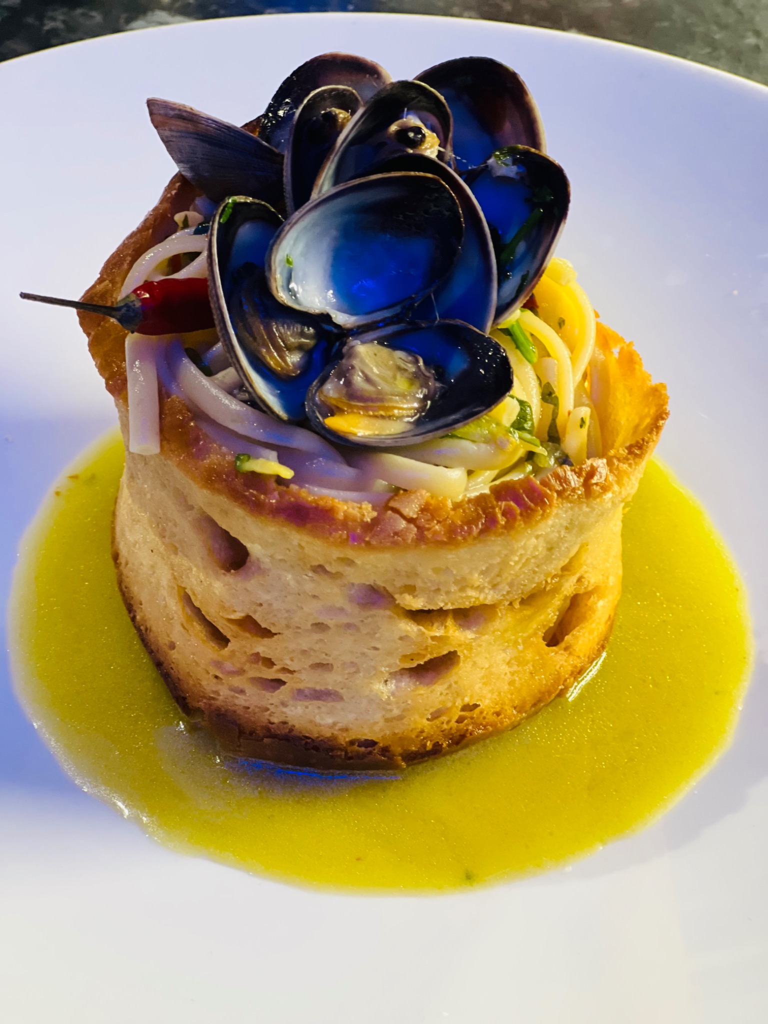 Pasta with clams served in a bread bowl on a white plate