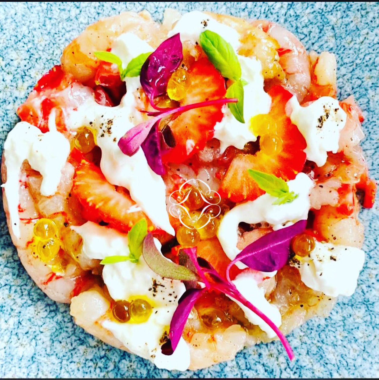 A circular arrangement with strawberry slices, cream, small leaves and golden pearls around the Gola emblem